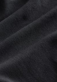 Czarna tkanina o gładkiej fakturze i subtelnym wzorze splotu, ukazująca delikatne linie i refleksy światła na swojej powierzchni.