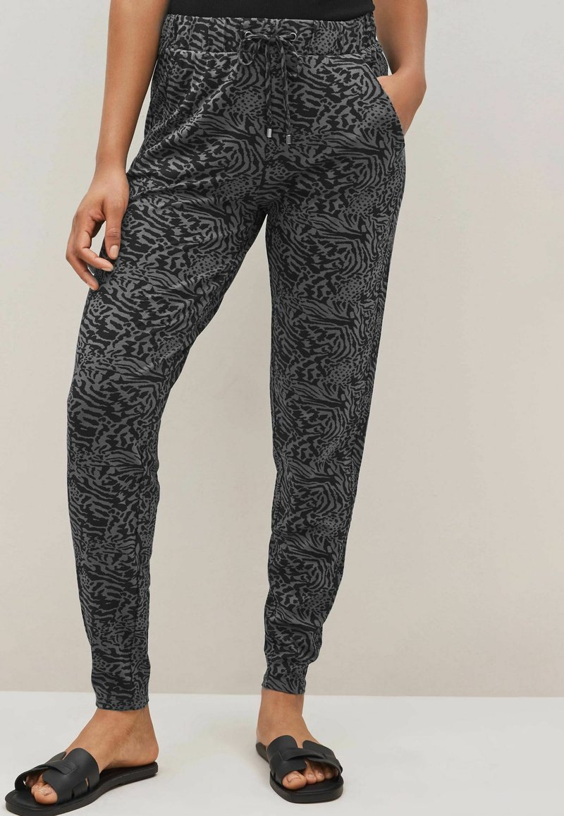 Zwarte en grijze gemusterde joggers met een elastische tailleband, zijzakken en een taps toelopend ontwerp. Het materiaal lijkt lichtgewicht en zacht.