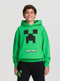 Felpa con cappuccio verde di Minecraft con grafica del volto nero del Creeper. Presenta una tasca a marsupio e polsini a costine. Abbinata a pantaloni neri con accenti verdi.