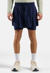 Shorts de course bleu marine avec une taille élastique et une doublure intérieure, associés à des baskets claires et des chaussettes blanches chevillées.