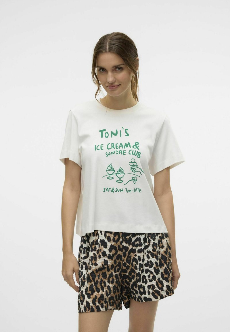 Witte katoenen t-shirt met groene graphics met de tekst "Toni's Ice Cream & Sundae Club," gecombineerd met zwart en bruin luipaardprint shorts.
