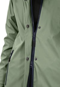 Green waterproof jacket featuring a zippered front, navy zippers, snap buttons, and a smooth, matte finish. Textured fabric visible.