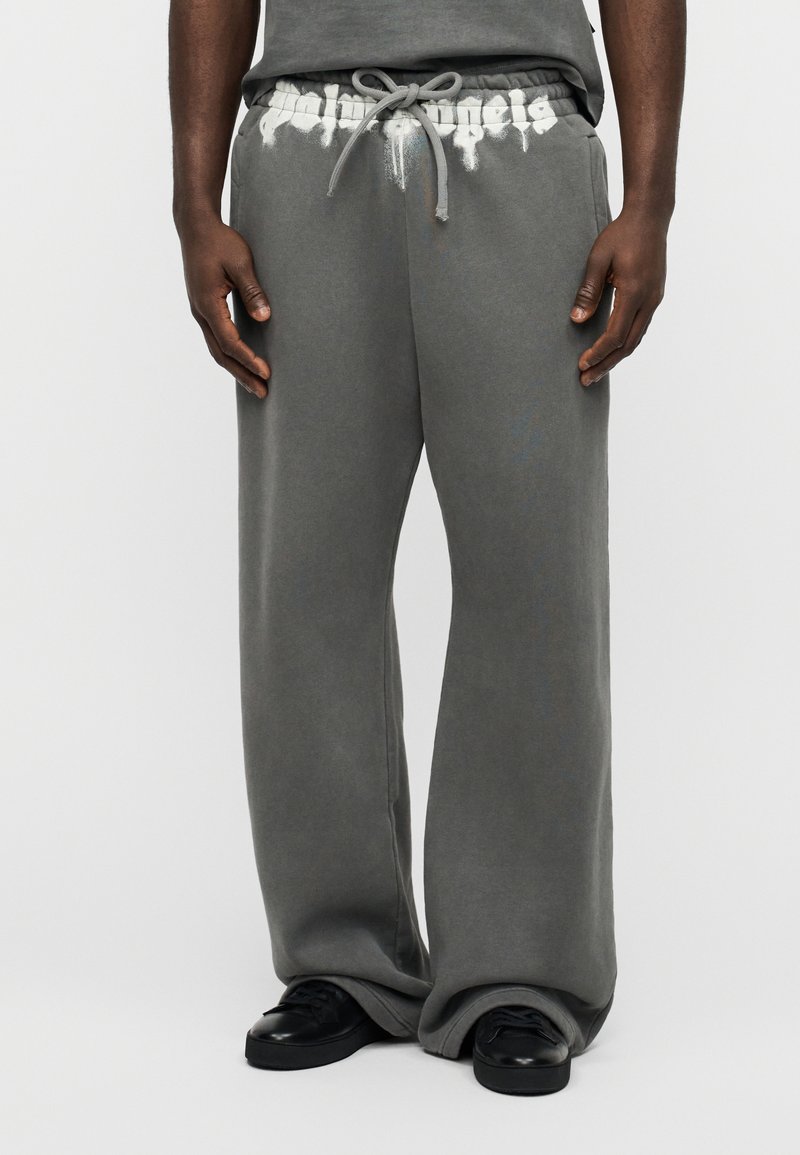 Γκρι φόρμες με άνετη εφαρμογή, κορδόνι στη μέση και λευκή εκτύπωση λογότυπου στη μέση. Λείο ύφασμα, λιτός σχεδιασμός.