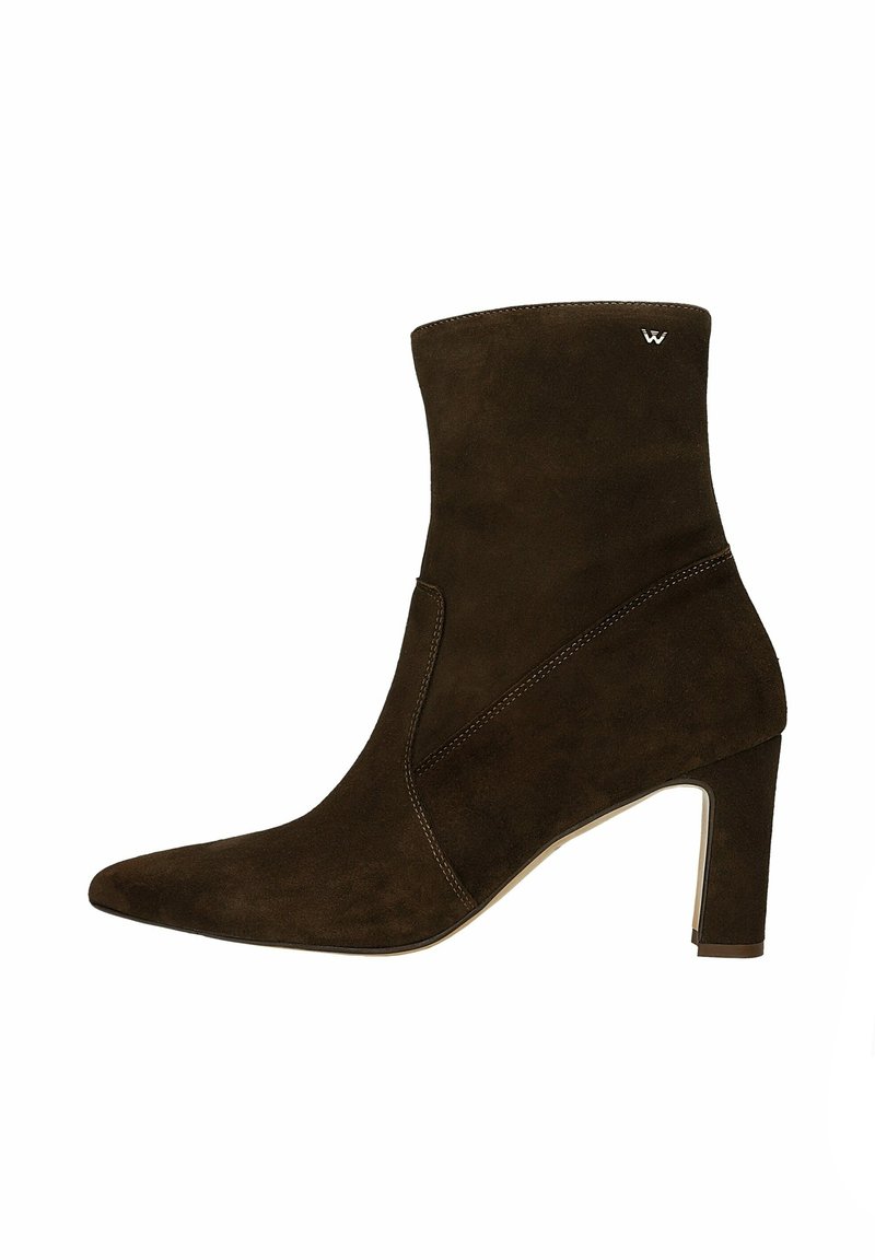 Bottines en daim marron avec un bout pointu et un talon aiguille. Présentent un design sans couture et des coutures discrètes en contraste.