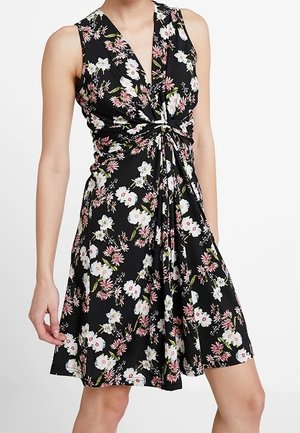 Mouwloze zwarte jurk met een roze en witte bloemenprint, met een gedraaide knoopdetail bij de taille en een V-hals.