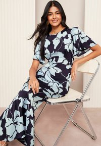 Abito maxi floreale con base blu navy e un motivo floreale oversize azzurro. Maniche corte, busto aderente e orlo svasato.