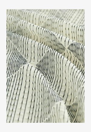 Tekstiil, millel on mustade joonte ja kujunditega tekstuuriga muster kreemjal taustal. Pehme kangas, mis langeb lainekujuliselt.