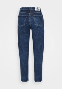 Jeans de mezclilla azul oscuro con un diseño de tiro alto, presentan dos bolsillos traseros y una etiqueta de marca en la cinturilla. Textura suave.