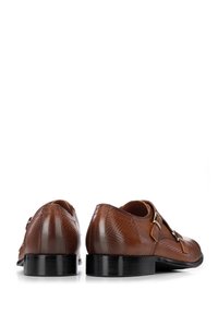 Zapatos de cuero marrón con un patrón de espiga texturizado, acentos de doble hebilla y una suela negra elegante. Vista trasera mostrada.