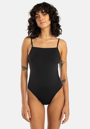 Zwarte badpak met dunne bandjes, vierkante halslijn, hoge uitsnijding aan de benen en een gladde, matte textuur. Minimalistisch ontwerp, zonder patronen of accenten.