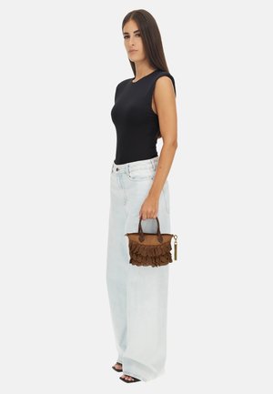 Sac en tissu marron avec des détails en feston, des poignées en cuir et une fermeture éclair dorée, associé à un haut sans manches noir et un jean large bleu clair.