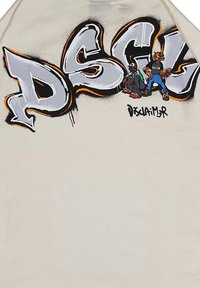 Maglietta color crema con una grande scritta in stile graffiti grigia e arancione "DSGL" decorata con personaggi dei cartoni animati e opere d'arte dettagliate.