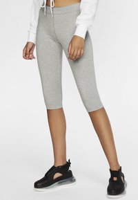 Šedé capri legíny vyrobené z měkkého, elastického materiálu, doplněné černými sportovními botami s elegantním designem a průhlednými podrážkami.