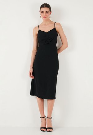 Crna midi haljina s tankim trakama, detaljem u obliku uvijanja na grudima i elegantnim krojem. Glatka tkanina i bočni prorez naglašavaju siluetu.