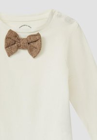 Roomkleurig shirt met lange mouwen en een gestructureerde bruine vlinderdas met een visgraatpatroon en twee drukknopen op de schouder.