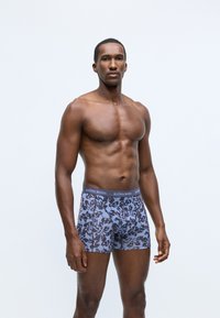 Kék virágmintás boxer alsónadrág szürke derékrésszel, amelyen a "BJÖRN BORG" logó található. Az anyag puha kinézetű, és testre simuló kialakítással bír.