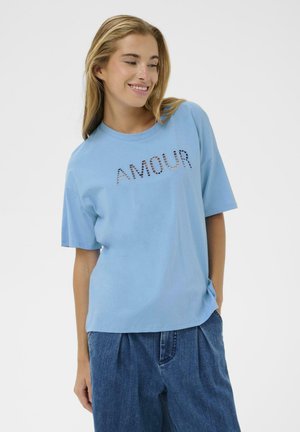 Tricou din bumbac bleu deschis cu mâneci scurte, cu cuvântul „AMOUR” imprimat într-un mod decorativ. Stilizat cu pantaloni de blugi largi.