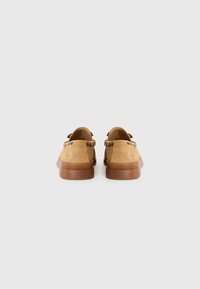 Chaussures en cuir suédé marron avec un profil bas, un bout rond et des semelles en caoutchouc. Présente des accents de couture et deux boucles latérales pour les lacets.