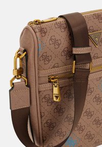 Borsa a tracolla marrone con motivo e hardware dorato. Presenta una chiusura con zip, una tracolla regolabile e un design con accento blu. Tessuto testurizzato.