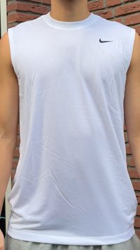 Ärmelloses weißes Sportshirt mit schwarzem Nike-Logo auf der oberen rechten Brust, getragen von einer Person, die an einer Backsteinmauer steht.