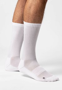 Weiße Sportsocken mit gerippter Textur, Netzakzenten und verstärkten Fersen- und Zehenbereichen. Klassisches Design geeignet für verschiedene Aktivitäten.