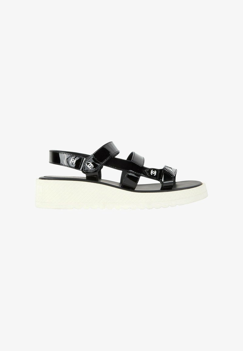 Sandale en cuir verni noir avec semelle plateforme blanche composée de trois brides, chacune avec un petit détail de logo blanc de la marque.