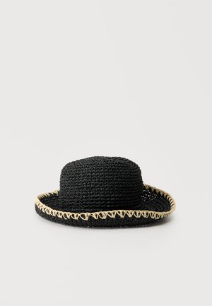 Cappello di paglia nero intrecciato con tesa larga e cuciture beige lungo il bordo, posto su uno sfondo chiaro uniforme.