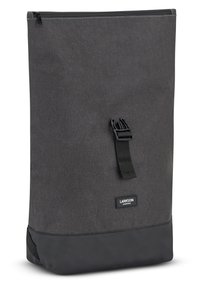 Mochila de tela gris con un cierre superior, con un fondo negro, correa ajustable y un parche con el logo. Diseño simple, forma rectangular.