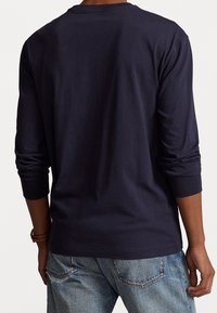 Navyblaues Langarm-T-Shirt aus weicher Baumwolle, mit Rundhalsausschnitt und eng anliegenden Bündchen. Die Rückseite ist glatt und ohne sichtbare Logos oder Muster.