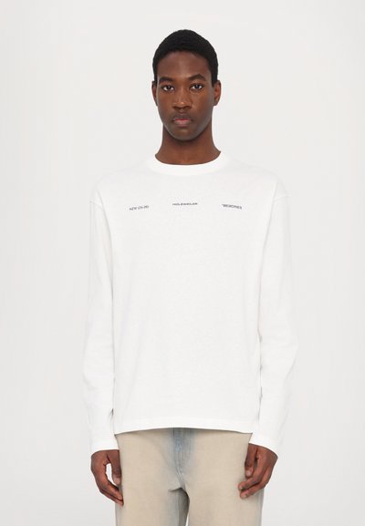 Hvit langermet bomull T-skjorte med rund hals, med trykt tekst i svart, løs passform og rett falm. Minimalistisk design.
