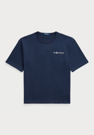 Tumši zils kokvilnas T-krekls ar īsām piedurknēm un apaļu kakla izgriezumu, ar mazu baltu logotipu kreisajā krūtīs. Vienkāršs, vienkrāsains dizains.