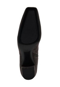 Talons en suède noir à forme arrondie, semelle texturée avec nervures, et détail d'accent subtil sur le côté.