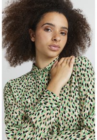 Blusa a maniche lunghe in tessuto leggero con una stampa leopardata astratta multicolore nei toni del verde, nero e beige.