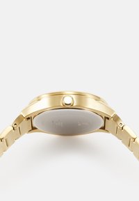 Goldfarbener Metallarmbanduhr mit einem runden Gehäuse, strukturiertem Finish und einer auffälligen Krone. Verfügt über ein Gliederarmband und eine glatte Rückseite.