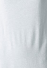 Vaaleansininen puuvillakangas, jonka pinta on sileä ja jossa on hienovaraisia ryppyjä. Kankaassa on pehmeä viimeistely, eikä siinä ole näkyviä kuvioita tai kiinnityselementtejä.