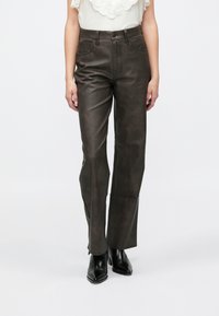 Pantalon en similicuir marron foncé, taille haute, coupe droite. Doté de poches avant et de détails de couture subtils.