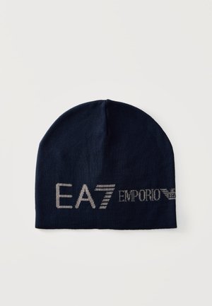 Mørkeblå strikket beanie med sølv "EA7 Emporio Armani" logo tekst på forsiden mod en lys baggrund.
