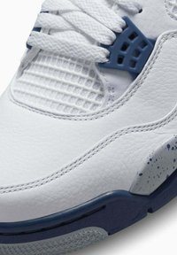 Sneaker bianco in pelle con pannelli in rete testurizzata, accenti blu navy e suola grigia macchiata. Caratterizzato da lacci piatti e cuciture rinforzate.