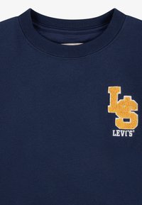 Námornícky modrá mikina s rebrovaným výstrihom. Na prednej strane sa nachádzajú žlté výšivky loga "LS" a "LEVI'S". Mäkčený materiál.
