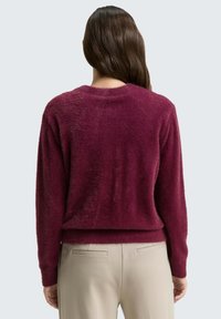 Bordeaux, fuzzy sweater met een ronde halslijn en lange mouwen, met een cropped ontwerp. Draag het met lichtbeige, op maat gemaakte broek.