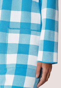 Gebreid jack met een groot blauw-wit ruitpatroon, diagonale strepen, een zak en een recht gesneden mouw.