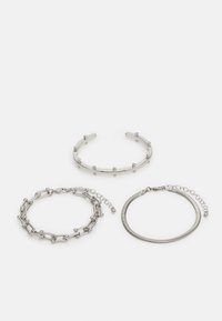 Three silver bracelets: a smooth open cuff with spherical accents, a linked chain bracelet, and a flexible round snake chain.