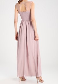 Abito maxi in morbido tessuto rosa, presenta un retro arricciato, spalline trasparenti e gonna fluida. Texture liscia con una gentle caduta e design con schiena aperta.
