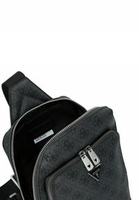 Black fabric crossbody bag with zippered compartments, featuring a subtle logo pattern, silver hardware, and a sleek triangular accent.