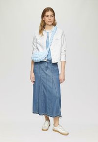 Hellblau geflochtene Umhängetasche, sanftes Design, aus Stoffmaterial, kombiniert mit einer weißen Jeansjacke und einem blauen Jeansrock. Legere Sneakers.