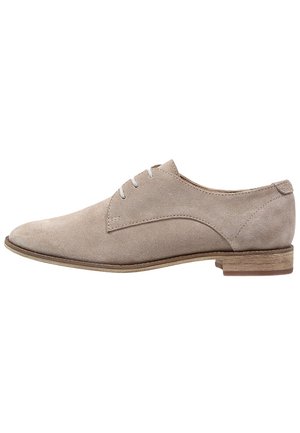 Beige ruskinds snørebånds oxford sko med rund tå og stakket trælav hæl, set fra siden på hvid baggrund.