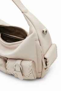 Sac à main en cuir beige clair au design décontracté. Il dispose d'un compartiment principal zippé et d'une poche latérale avec des détails tissés et des éléments en métal argenté.