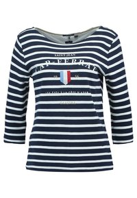 Marinblå och vit randig långärmad topp med vid halsringning. Har text och en sköldgrafik i röd, vit och blå. Blandat bomullstyg.