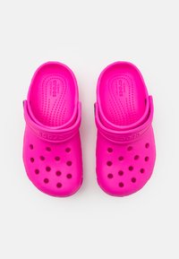 Crocs rosa realizzati in materiale leggero e testurizzato, dotati di fori di ventilazione, una cinghia posteriore e un sottopiede con puntini rialzati per il massimo comfort.