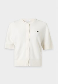 Cardigan blanc à manches courtes avec boutons, col rond et petit logo crocodile vert sur la poitrine gauche.